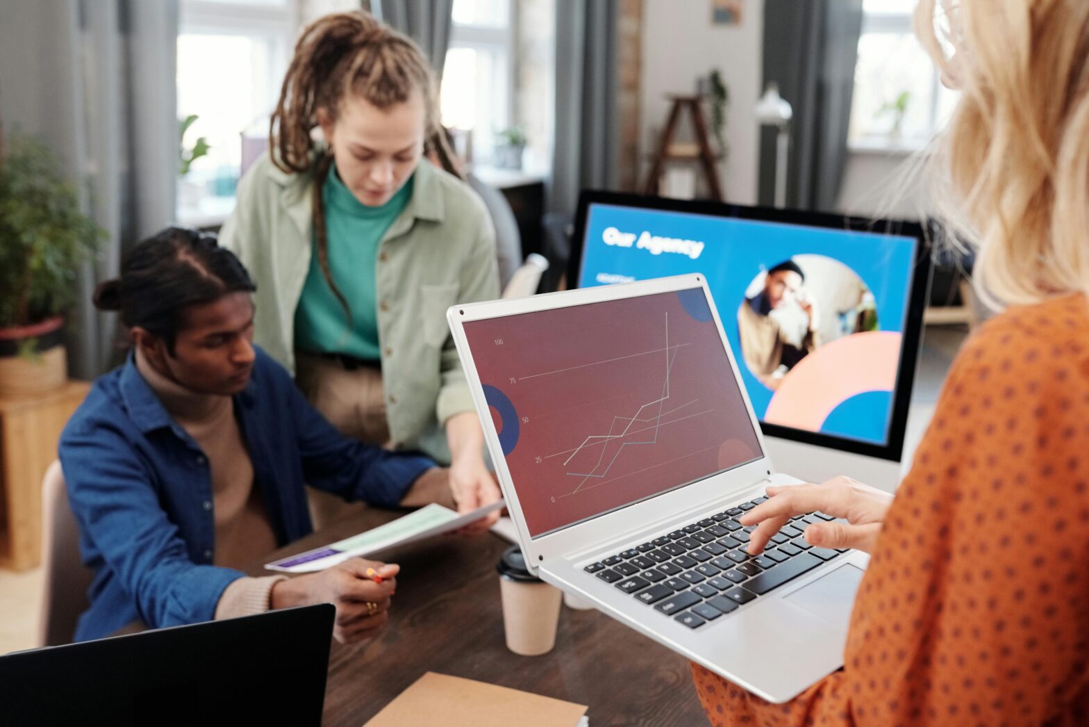 A collaborative office environment where professionals are working together, engaging in discussions and sharing ideas around a modern, open workspace.